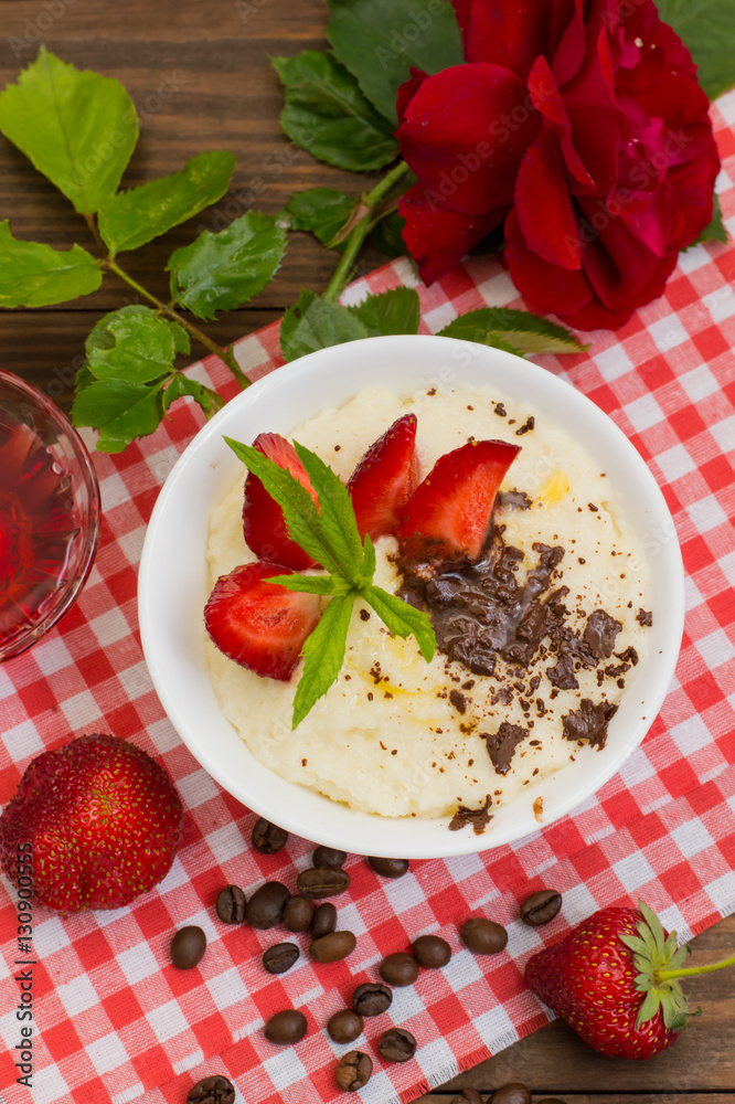 Semolina with grated chocolate and strawberry on a fabulously delicious tomorrow. Wooden background. Top view. Close-up Semolina with grated chocolate and strawberry on a fabulously delicious tomorrow. Wooden background. Top view. Close-up