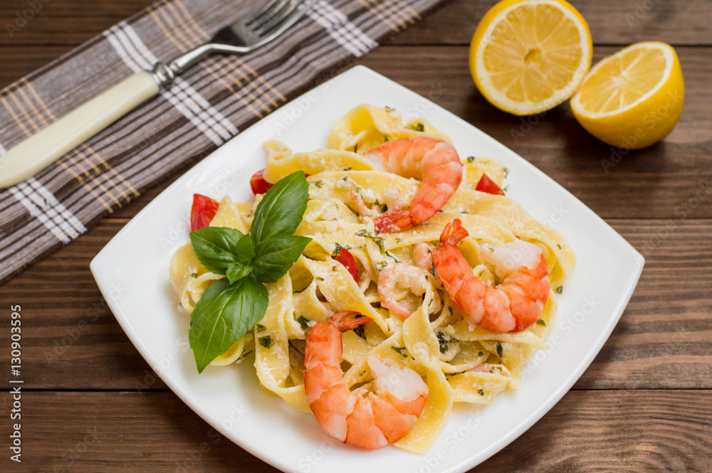 Fettuccine pasta in cream sauce with king prawns on a plate the wooden table. Horizontal view from above. Top . Close-up Fettuccine pasta in cream sauce with king prawns on a plate the wooden table. Horizontal view from above. Top . Close-up