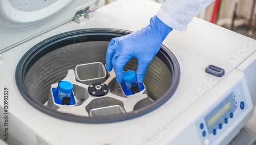 Technician loading a sample to centrifuge machine photo