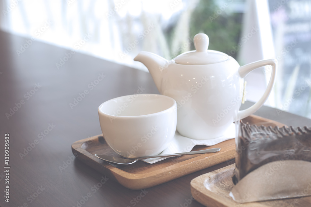 Teapot set on wood tray near chocolate cake on counter bar table 