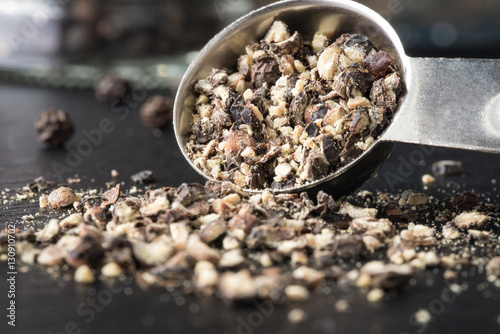 Canvas Print Coarsely ground black pepper spilling from a measuring spoon