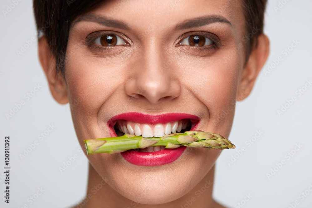 Healthy Eating. Beautiful Woman Holding Asparagus Between Teeth Healthy Eating. Beautiful Woman Holding Asparagus Between Teeth
