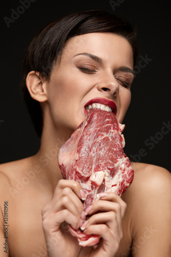 Eating Meat. Beautiful Woman Biting Raw Beef Steak Meat