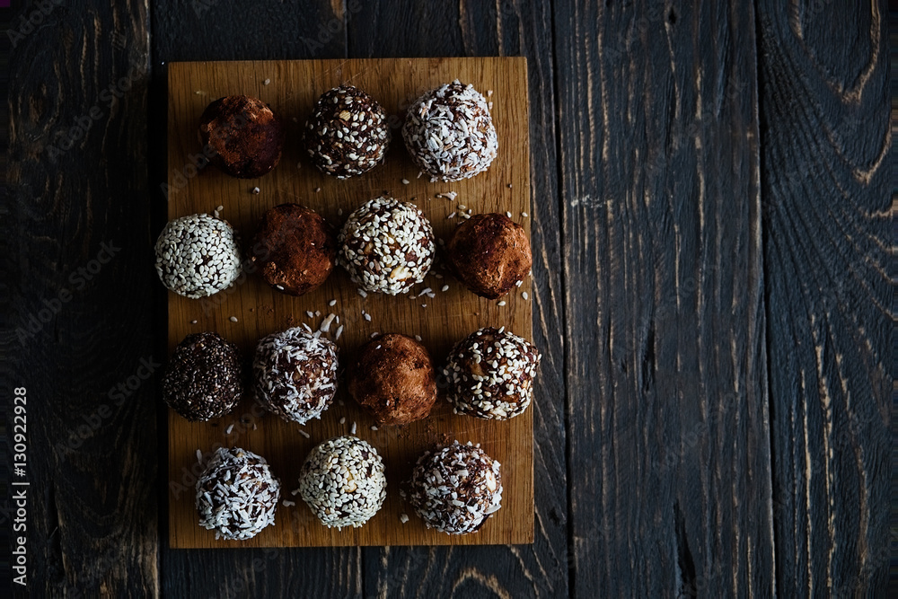 Healthy raw energy bites with cocoa, coconut, sesame, chia. Vegan chocolate truffles on a dark textured wooden background. Copy space Healthy raw energy bites with cocoa, coconut, sesame, chia. Vegan chocolate truffles on a dark textured wooden background. Copy space