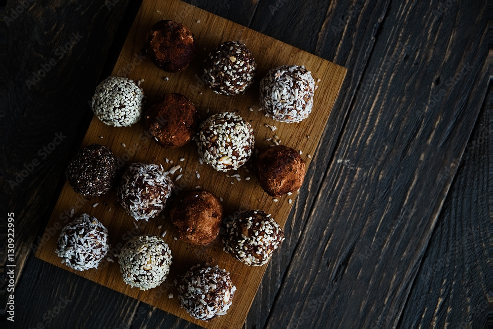 Healthy raw energy bites with cocoa, coconut, sesame, chia. Vegan chocolate truffles on a dark textured wooden background. Copy space