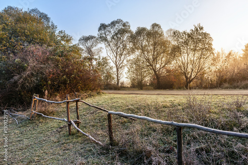 wooden fence in fog on frozen meadow at sunrise