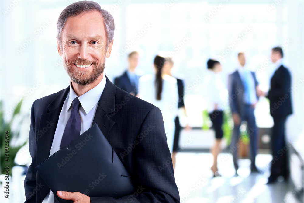 Happy mature business man looking at camera with satisfaction at office Happy mature business man looking at camera with satisfaction at office