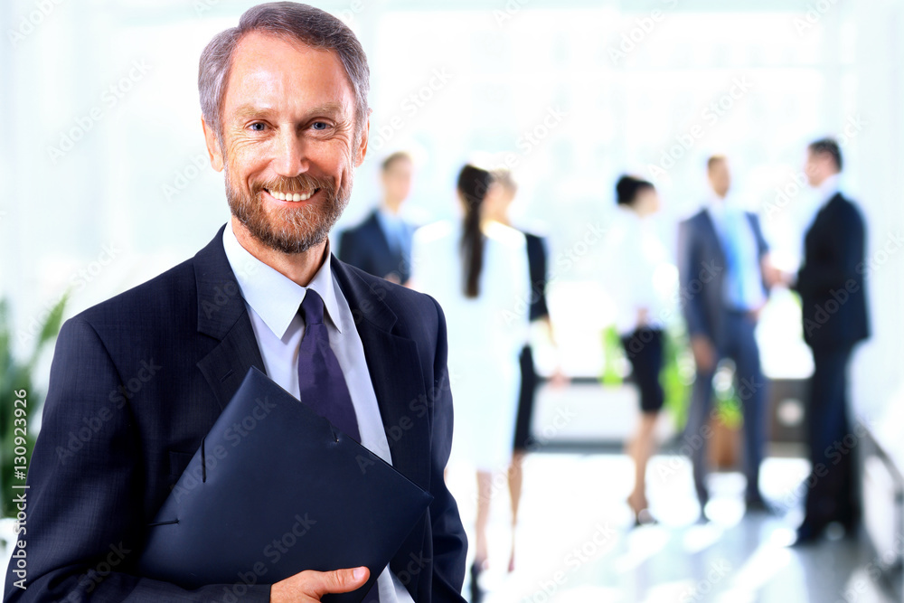Happy mature business man looking at camera with satisfaction at office Happy mature business man looking at camera with satisfaction at office