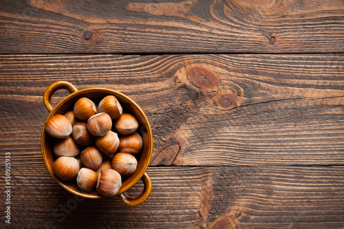 Hazelnuts in a porcelain bowl on a wooden background