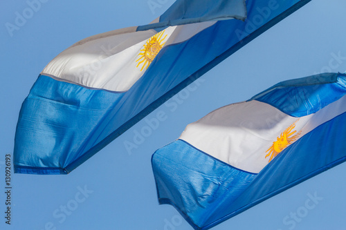 Two argentine flag waves against blue sky