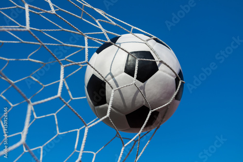 soccer ball in goal net with blue sky