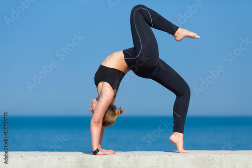 Young sportswoman doing exercises against the sea