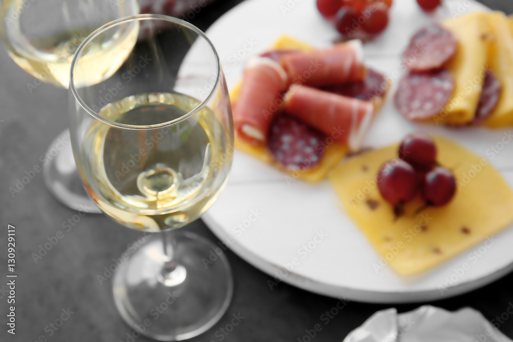 Glasses with white wine and tasty snacks on a table