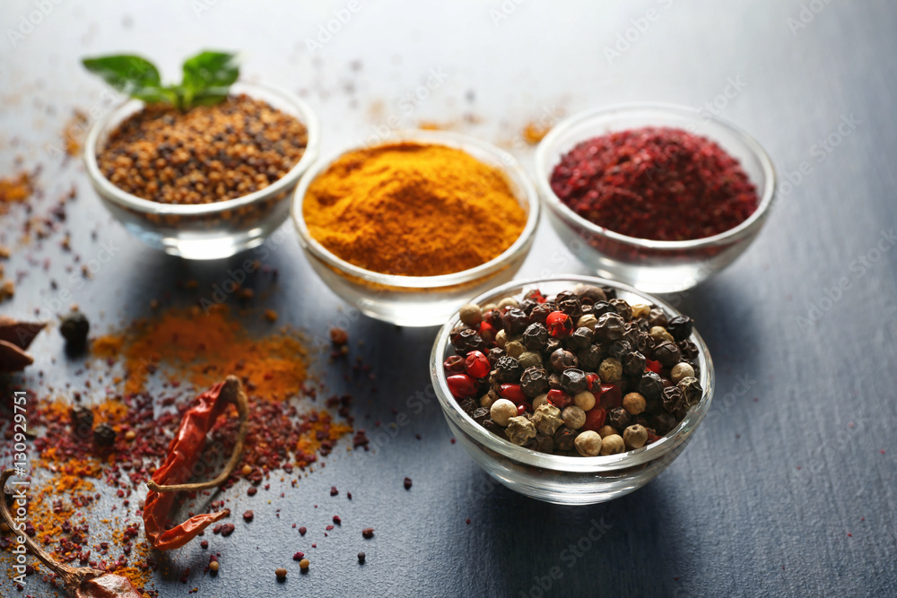 Aromatic spices in glass bowls on grey background Aromatic spices in glass bowls on grey background