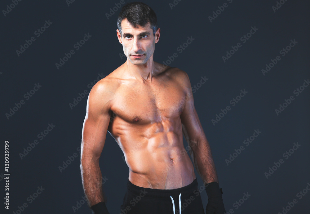 Strong athletic man standing on black background