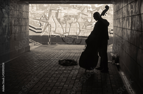 Street musician playing on doublebass in the underpass