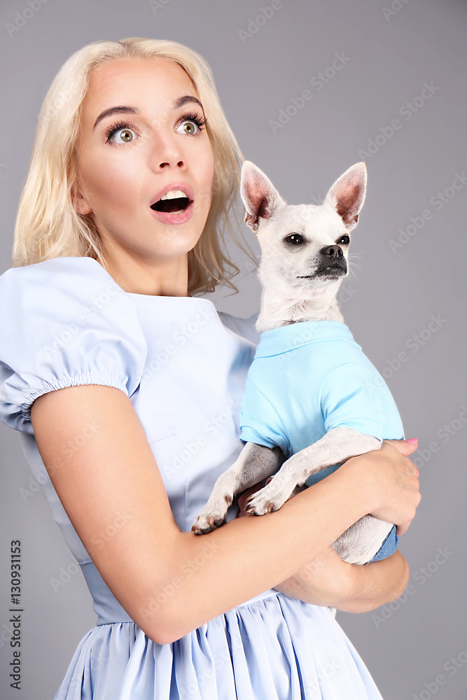 Beautiful girl holding cute dog on grey background Beautiful girl holding cute dog on grey background