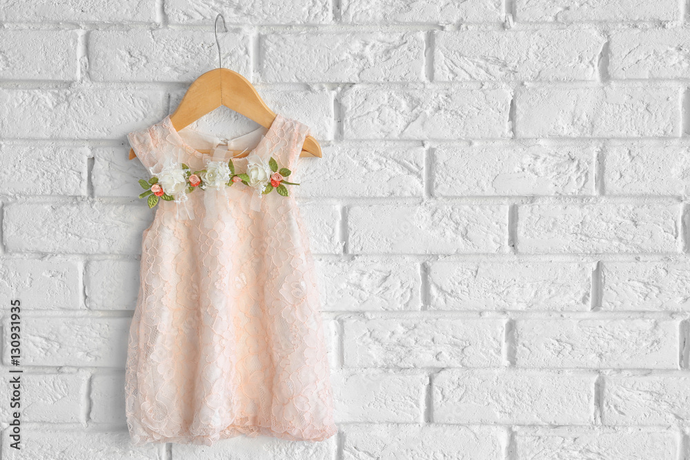 Fashion baby girl dress hanging on white brick wall background