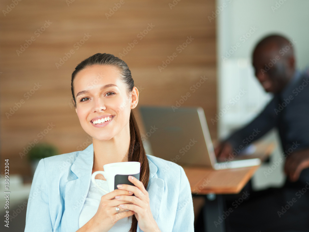 Attractive woman sitting at desk in office, working with laptop , having takeaway coffee Attractive woman sitting at desk in office, working with laptop , having takeaway coffee