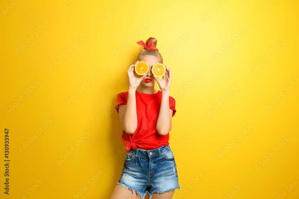 Young beautiful woman with orange on yellow background Young beautiful woman with orange on yellow background