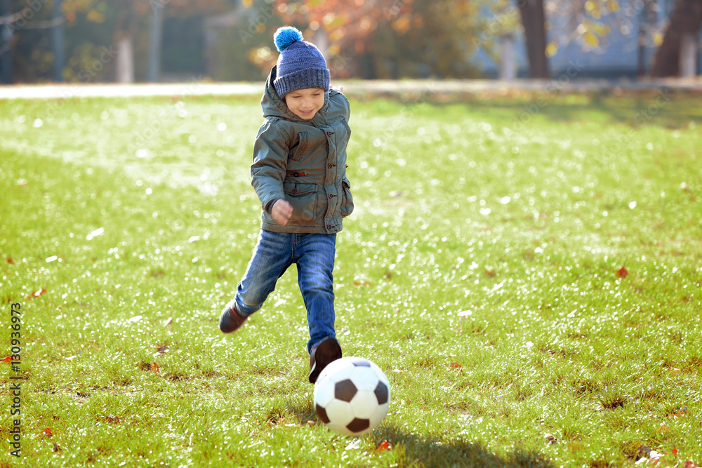 Cute little boy playing football on soccer pitch Cute little boy playing football on soccer pitch