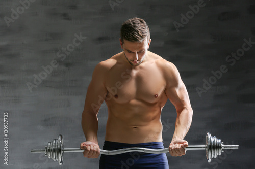 Sporty man doing exercises with barbell on dark background © Africa Studio