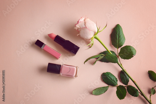 Rose and makeup products on color background