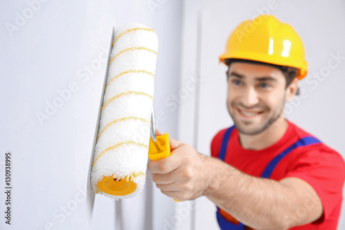 Young worker painting wall ...