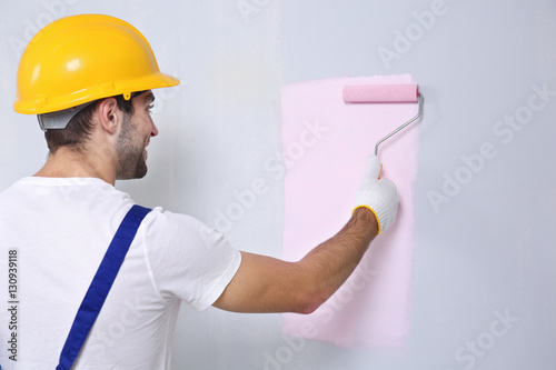 Obraz na płótnie Young worker painting wall in room