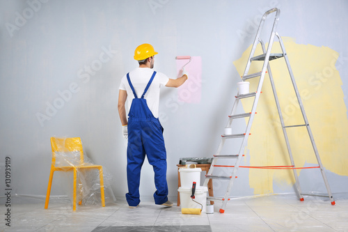 Young worker painting wall ...