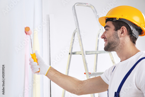 Young worker painting wall ...
