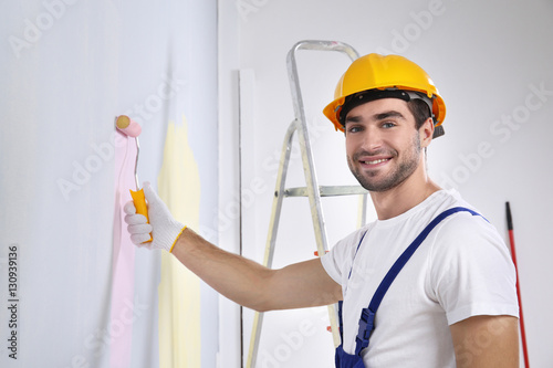 Young worker painting wall ...
