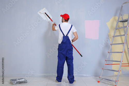 Young worker painting wall ...