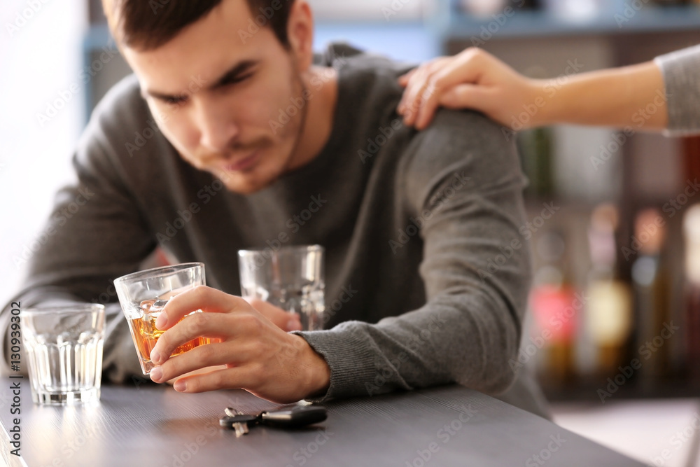 Man with car key and alcoholic beverage in bar. Don't drink and drive concept