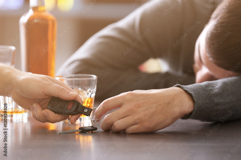 Woman taking car key from drunk man in bar, closeup. Don't drink and drive concept Woman taking car key from drunk man in bar, closeup. Don't drink and drive concept