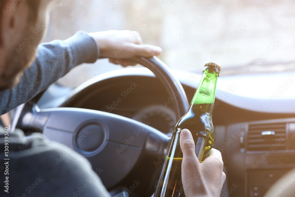 Foto Stock Man holding bottle of beer while driving car, closeup. Don't ...