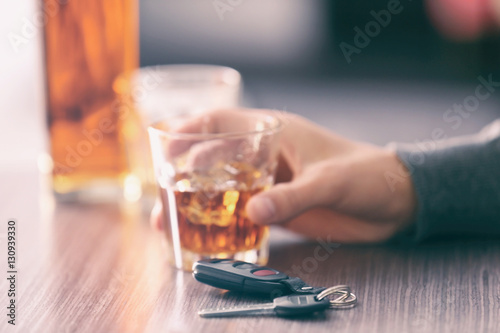 Man sitting in bar with alcoholic beverage and car key, closeup. Don't drink and drive concept