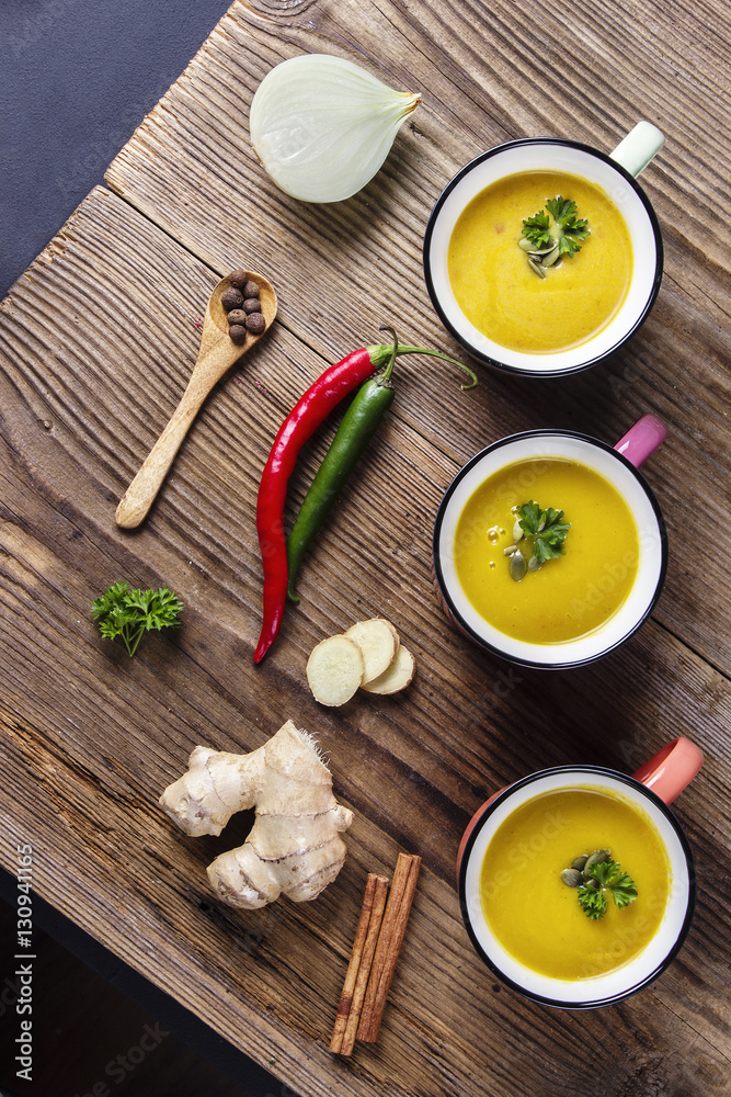 Pumpkin soup in enamel mugs, pumpkin seeds and parsley, view fro