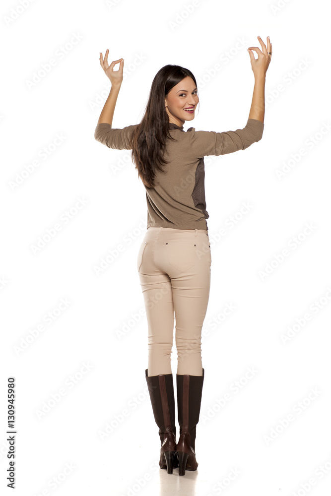back view of young woman holding an imaginary object over her head back view of young woman holding an imaginary object over her head