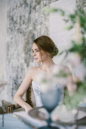 Portrait of young beautiful modern sitting in a armchair bride in a grey lace dress.