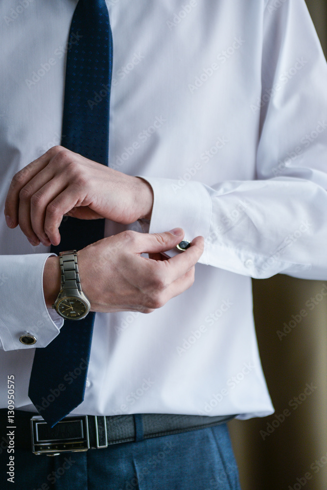 man in a tux fixing his cufflink