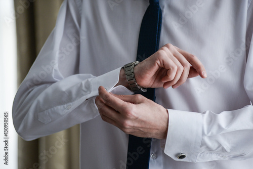 man in a tux fixing his cufflink
