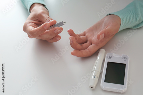 Woman checking blood sugar level by glucometer and test stripe at home photo