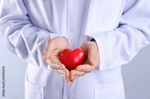 Male doctor hands holding red heart on light background