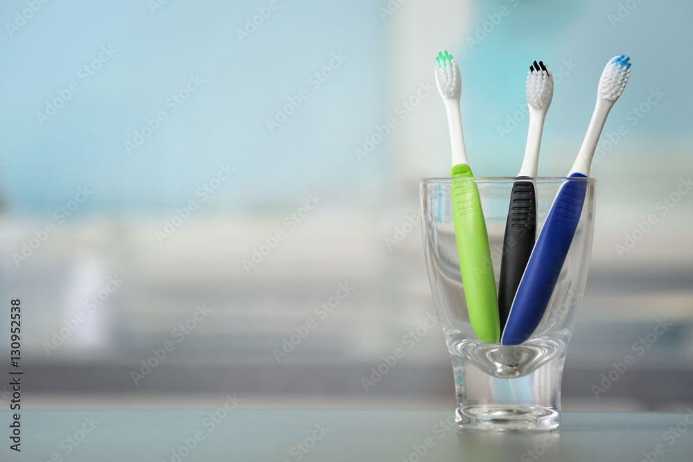 Toothbrushes in glass on blurred background Toothbrushes in glass on blurred background