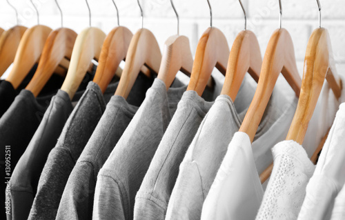 Black, grey and white t-shirts on hangers, close up view