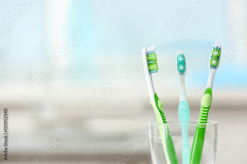 Toothbrushes in glass on blurred background