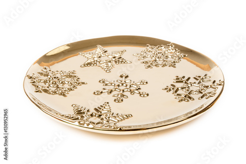Luxurious gold plate decorated with winter ornaments – snowflakes.  Round gold plate, isolated on white background.  Winter, Christmas, New Year decoration. Side view.