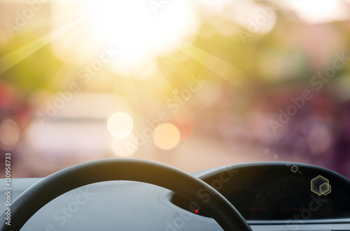 Inside car view ,steering wheel on blur traffic road with colorful bokeh light abstract background.
