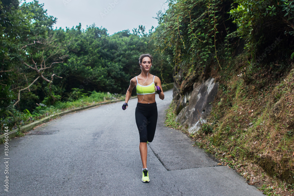 Female sport model running on road in mountains. Fitness woman training outdoors.